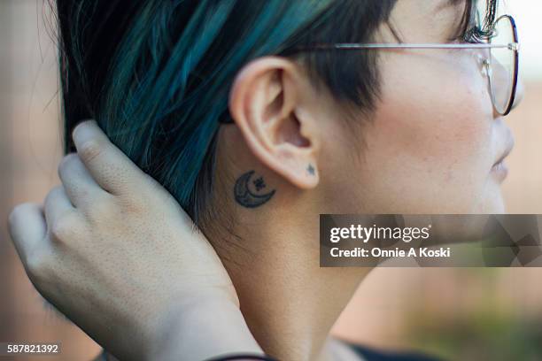Shibuya, Tokyo A closeup of Ai Miyata's tattoos, a crescent moon and star behind her ear, and a small star over her pierced earlobe, on August 07,...