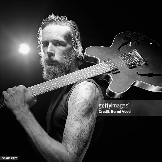 tattooed man holding guitar - músico de rock fotografías e imágenes de stock