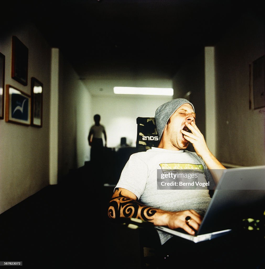 Trendy Man Using Laptop and Yawning
