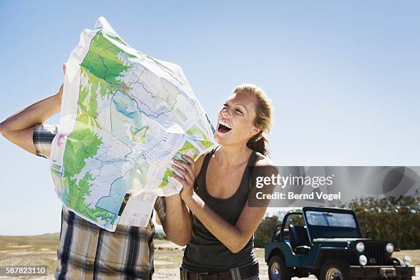 playful couple looking at map - schlechte luft stock-fotos und bilder