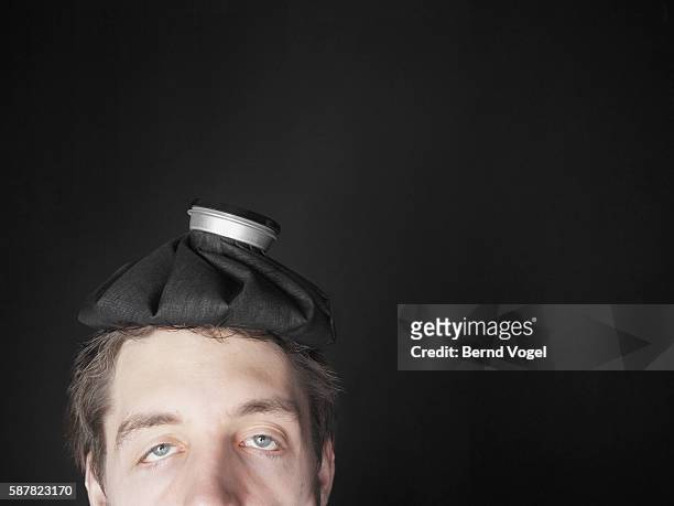 young man with hot water bottle on his head - hungover stock pictures, royalty-free photos & images
