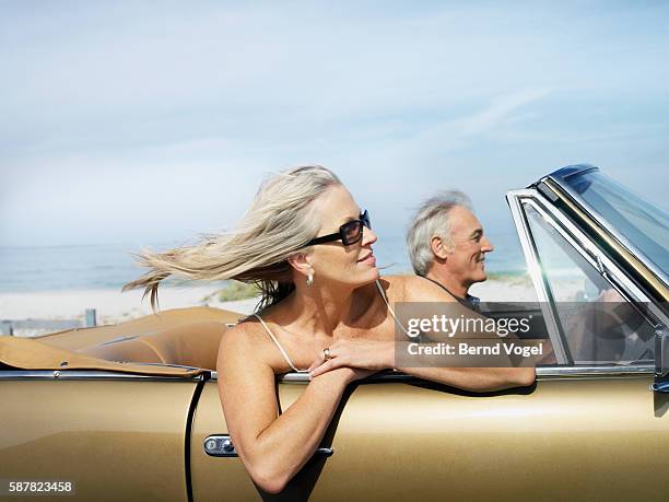 couple riding in convertible on oceanfront road - auto alt stock-fotos und bilder