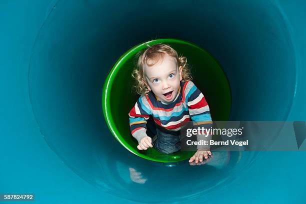 boy crawling inside plastic tunnel - indoor kids play area stock-fotos und bilder