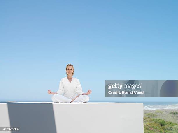 woman doing yoga outdoors - lotussitz stock-fotos und bilder