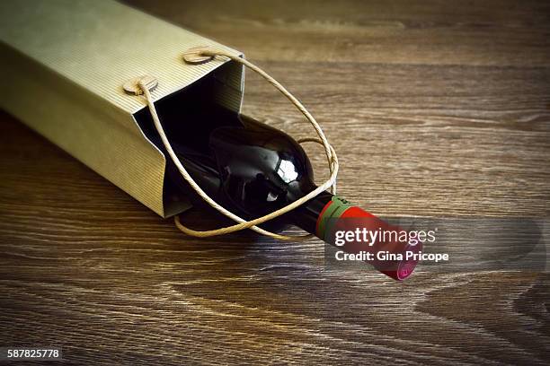 bottle of red wine in a bag on wooden background. - wine gift stock pictures, royalty-free photos & images