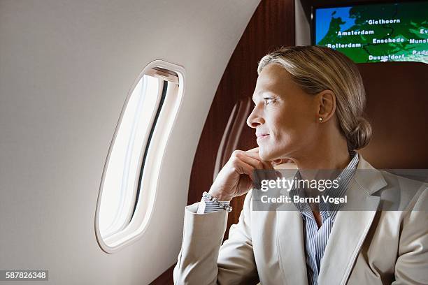 executive looking out of window on airplane - reichtum stock-fotos und bilder