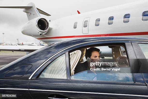 businessman using cell phone in car on airport runway - private wealth stock pictures, royalty-free photos & images