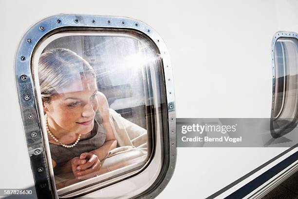 woman looking out an airplane window - airplane window exterior stock-fotos und bilder
