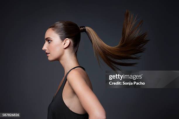 studio shot of young woman tossing hair - queue de cheval photos et images de collection