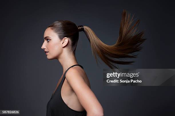 studio shot of young woman tossing hair - ponytail hairstyle stock pictures, royalty-free photos & images