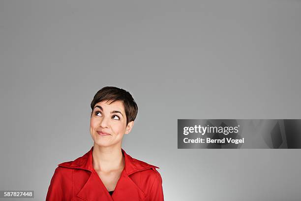 studio portrait of mid adult woman wearing red coat - woman looking up bildbanksfoton och bilder