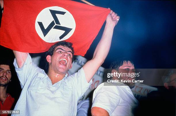 White South African man holds up a flag for the Afrikaner Resistance Movement , disrupting a National Party meeting in Pietersburg.