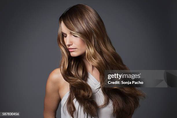 studio portrait of young woman with long brown hair - cabello castaño fotografías e imágenes de stock