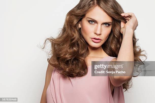 studio portrait of young brunette woman - 髪に手をやる　女性 ストックフォトと画像