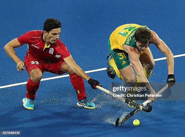 Fergus Kavanagh of Australia pushes the ball past Tanguy Cosyns of Belgium during the hockey game on Day 4 of the Rio 2016 Olympic Games at the...