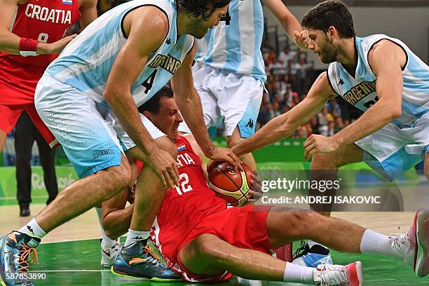 Croatia's centre Darko Planinic holds on to the ball next to Argentina's power forward Luis Scola and Argentina's shooting guard Patricio Garino...