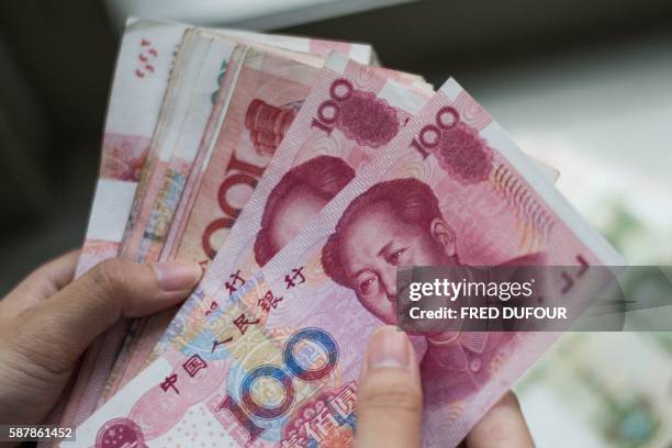 This photo illustration taken on August 9, 2016 shows Chinese 100 yuan notes in Beijing. - A year ago on August 11, 2015 Chinese authorities stunned...