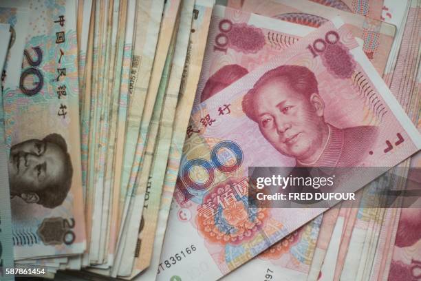 This photo illustration taken on August 9, 2016 shows Chinese 100 yuan notes in Beijing. - A year ago on August 11, 2015 Chinese authorities stunned...