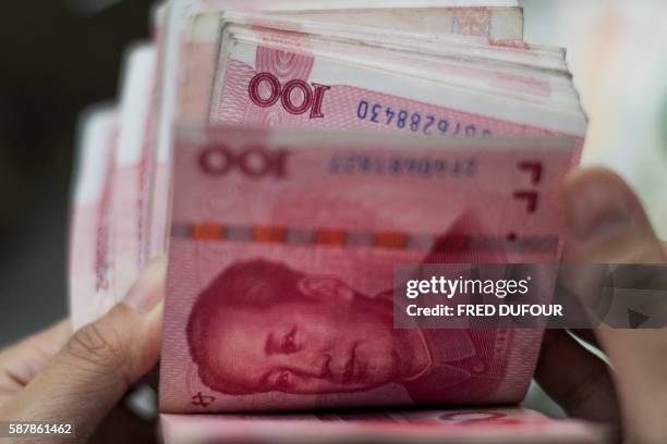 This photo illustration taken on August 9, 2016 shows Chinese 100 yuan notes in Beijing. - A year ago on August 11, 2015 Chinese authorities stunned...