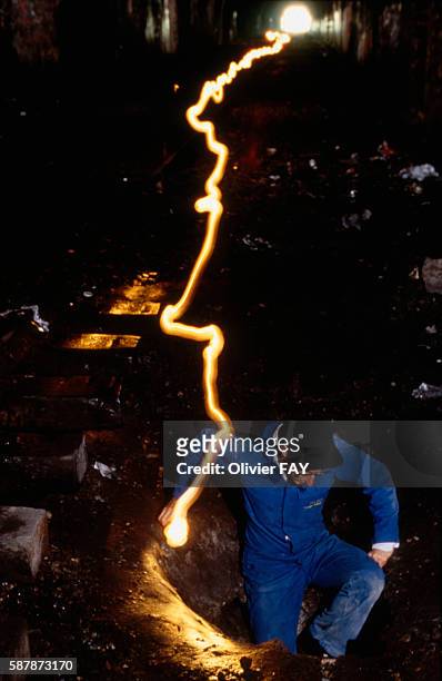 The trail of a light carried by a man exploring the dark catacombs of Paris. One of the entrances of the quarries.