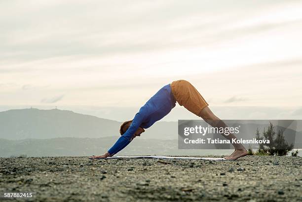 man practicing yoga outdoors - downward facing dog position stock pictures, royalty-free photos & images