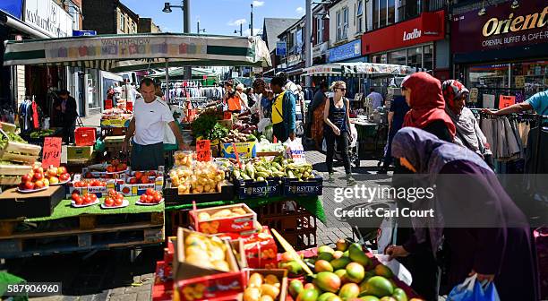 People browse items on sale at stalls in Walthamstow market on August 9, 2016 in London, England. Walthamstow Market in north east London is believed...