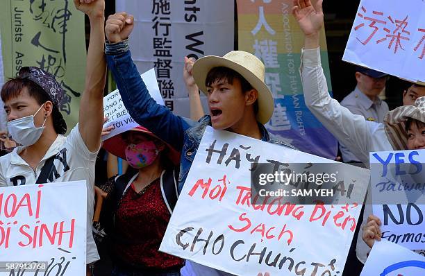 Vietnamese working in Taiwan display placards reading "Give back the clean ocean to us" as they demonstrate outside the Formosa Plastics Corporation...
