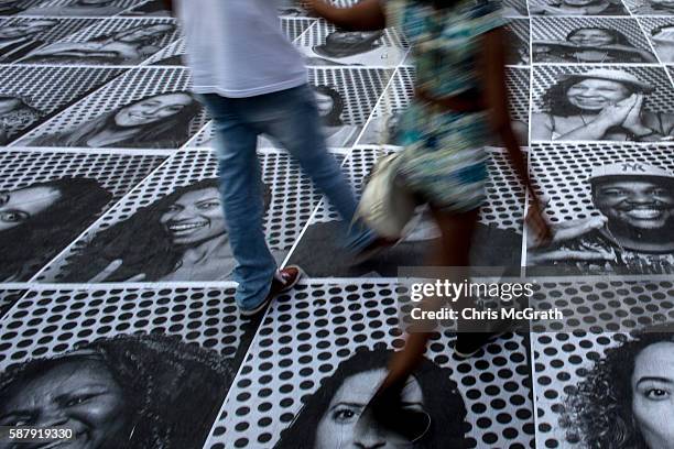 People walk on portraits produced by artist JR for his inside out project on August 8, 2016 in Rio de Janeiro, Brazil. The artist JR has unveiled...