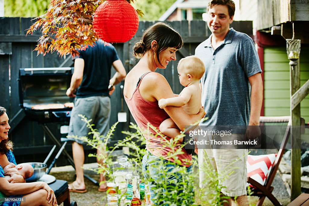 Mother holding infant daughter during barbecue
