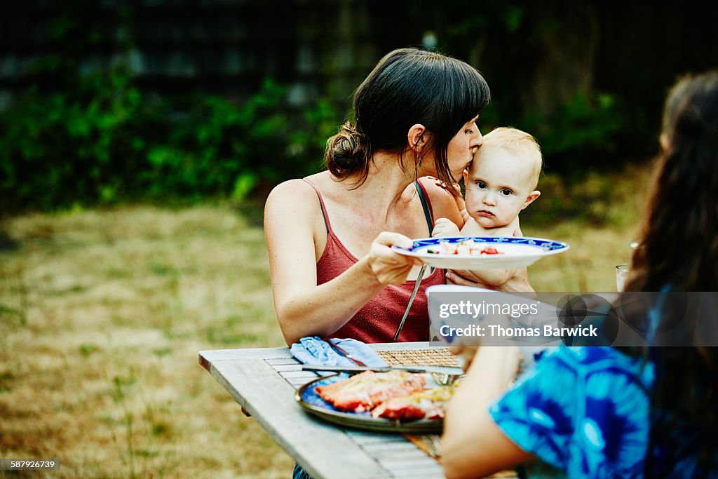 Mother kissing daughter on head during barbecue