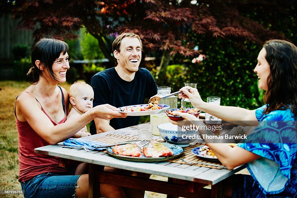 Laughing families sharing dinner in backyard