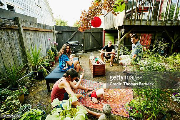 two couples with babies gathered on patio of home - holzbank stock-fotos und bilder