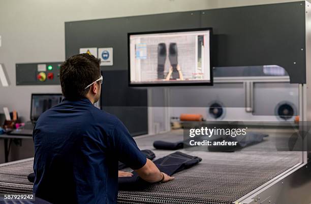 man operating a laser machine at a clothing factory - textile printing stock pictures, royalty-free photos & images