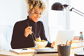 Afro american young woman eating lunch at the desk