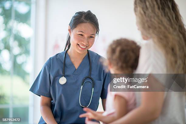 nurse speaking to a mother and child - medical building 個照片及圖片檔