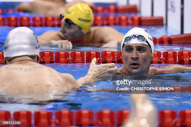 S Ryan Lochte talks with Brazil's Henrique Rodrigues after they competed in a Men's 200m Individual Medley heat during the swimming event at the Rio...