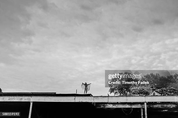 Woman wearing a cape stands on top of the ruins of a building in an industrial zone in the Bushwick section of Brooklyn, New York.