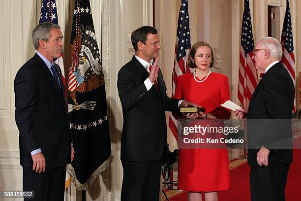 President Bush looks on as John Roberts is sworn in by Justice John Paul Steven, right, as 17th Chief Justice of the United States in the East Room...