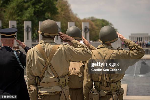 Reenactment soldiers from Ft. Myer salutes as vintage WWII planes perform the "missing man formation," during a diverse array of World War II...