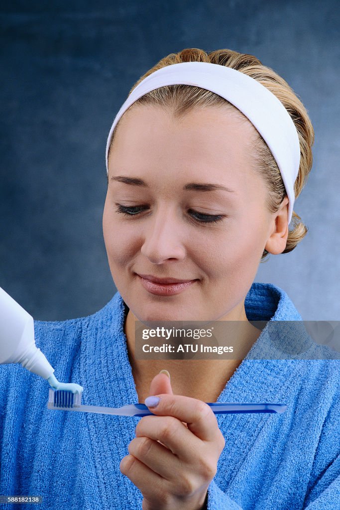 Woman Putting Toothpaste on Toothbrush