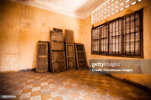 window shutters and wood panels against wall in empty room, s21 prison, phnom penh, cambodia - phnom penh stock pictures, royalty-free photos & images