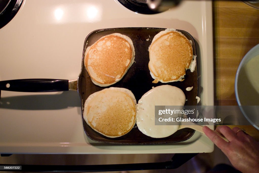 Pancakes on Skillet, One being Flipped