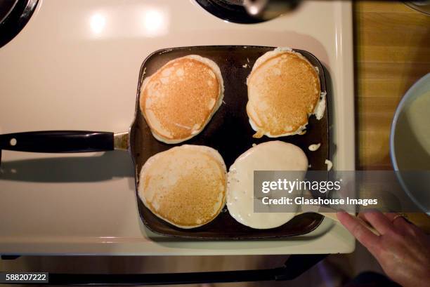 pancakes on skillet, one being flipped - pancake turner stock pictures, royalty-free photos & images