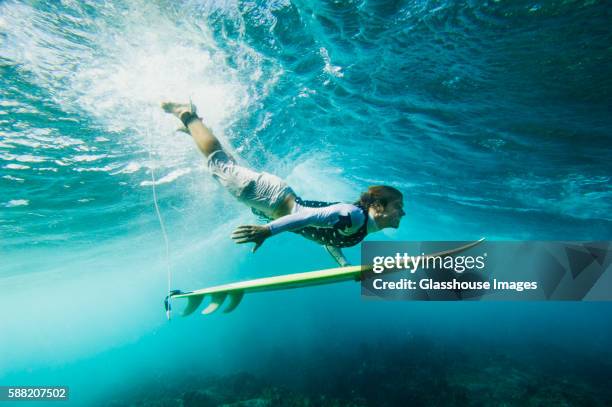 surfer and surboard diving under wave - mauritius stock-fotos und bilder