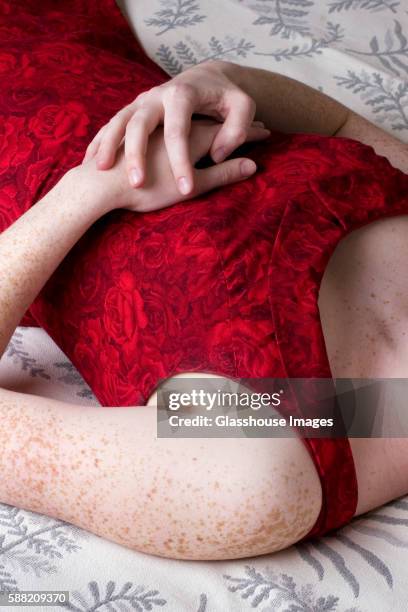 freckled girl in red dress laying down on bed - freckle arm stock pictures, royalty-free photos & images