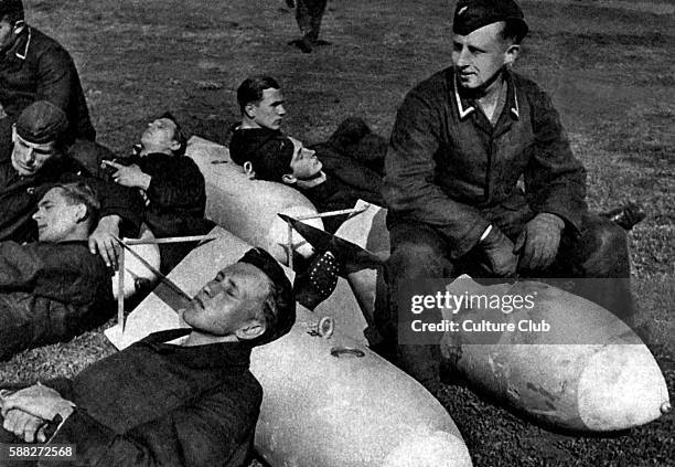 German soldiers resting on bombs. Postcard published by Der Adler, illustrated magazine of the German Luftwaffe. C. 1942. Caption: Auf Bomben schläft...