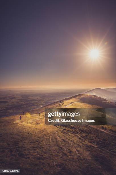 group of people walking along path atop hill with bright sun - worcestershire stock pictures, royalty-free photos & images