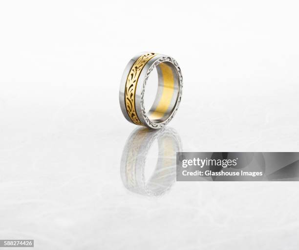 gold and silver ring on reflective surface - silver ring stock pictures, royalty-free photos & images