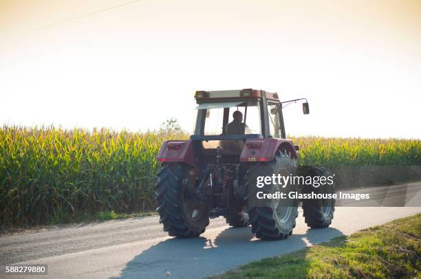 tractor driving on rural road - farm equipment stock pictures, royalty-free photos & images