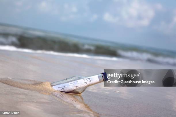 message in bottle at water's edge - message in a bottle stock pictures, royalty-free photos & images